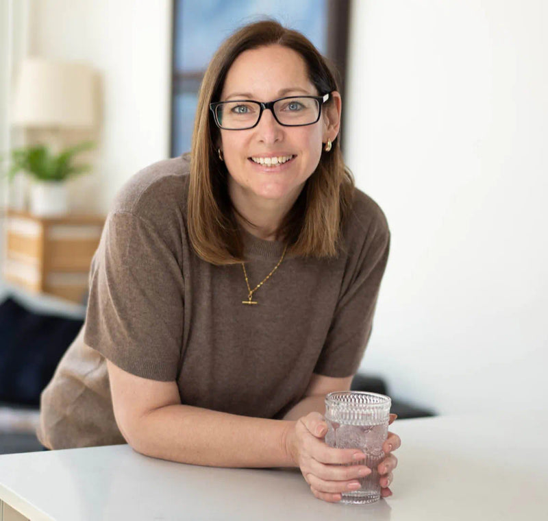 Woman holding a glass of water in an indoor setting