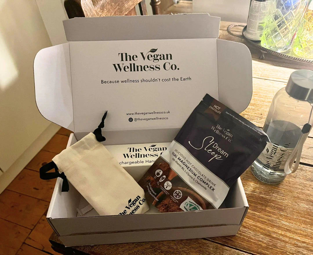 Box from The Vegan Wellness Co. containing various products on a wooden surface.