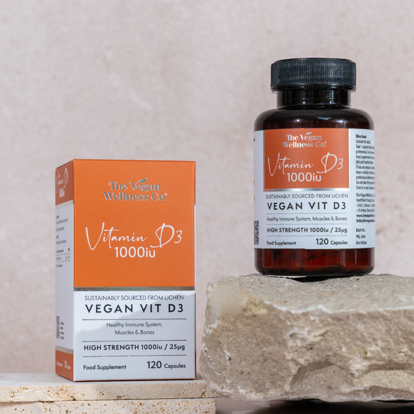 Vegan Vit D3 supplement bottle and packaging on a stone surface with a neutral background