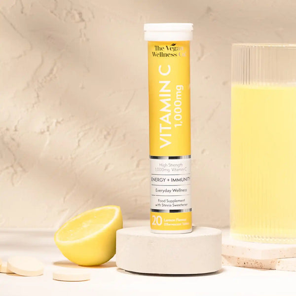 Vitamin C supplement tube with a glass of yellow liquid and lemon on a beige background