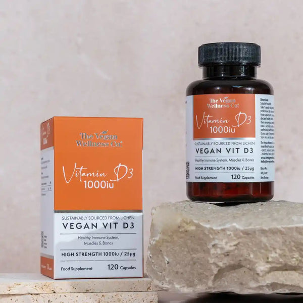 Vegan Vit D3 supplement bottle and packaging on a stone surface with a neutral background